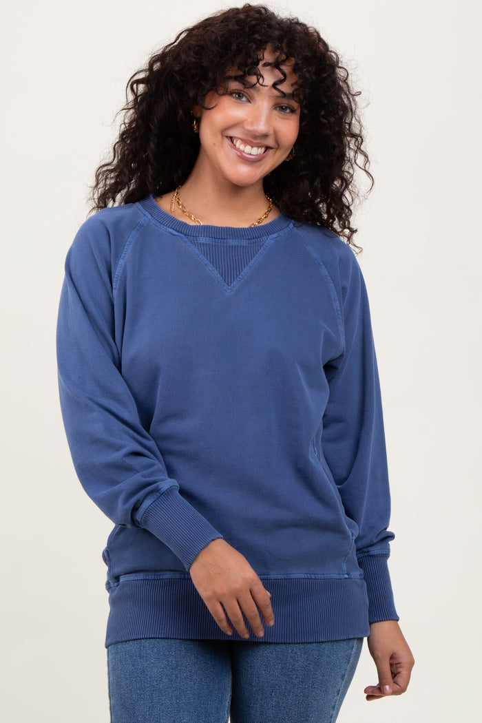 woman wearing a blue casual sweatshirt with a relaxed fit and ribbed hem, smiling at the camera
