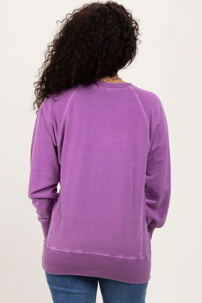 woman wearing a solid purple sweatshirt with a relaxed fit and ribbed cuffs, viewed from the back