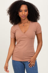 woman wearing a light brown ribbed short sleeve top with a v-neck and fitted style, paired with blue jeans