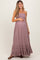 woman wearing a mauve maternity maxi dress with spaghetti straps and ruffled hem, holding her baby bump