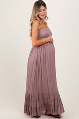 woman wearing a dusty mauve maternity maxi dress with ruffled hem and holding her baby bump