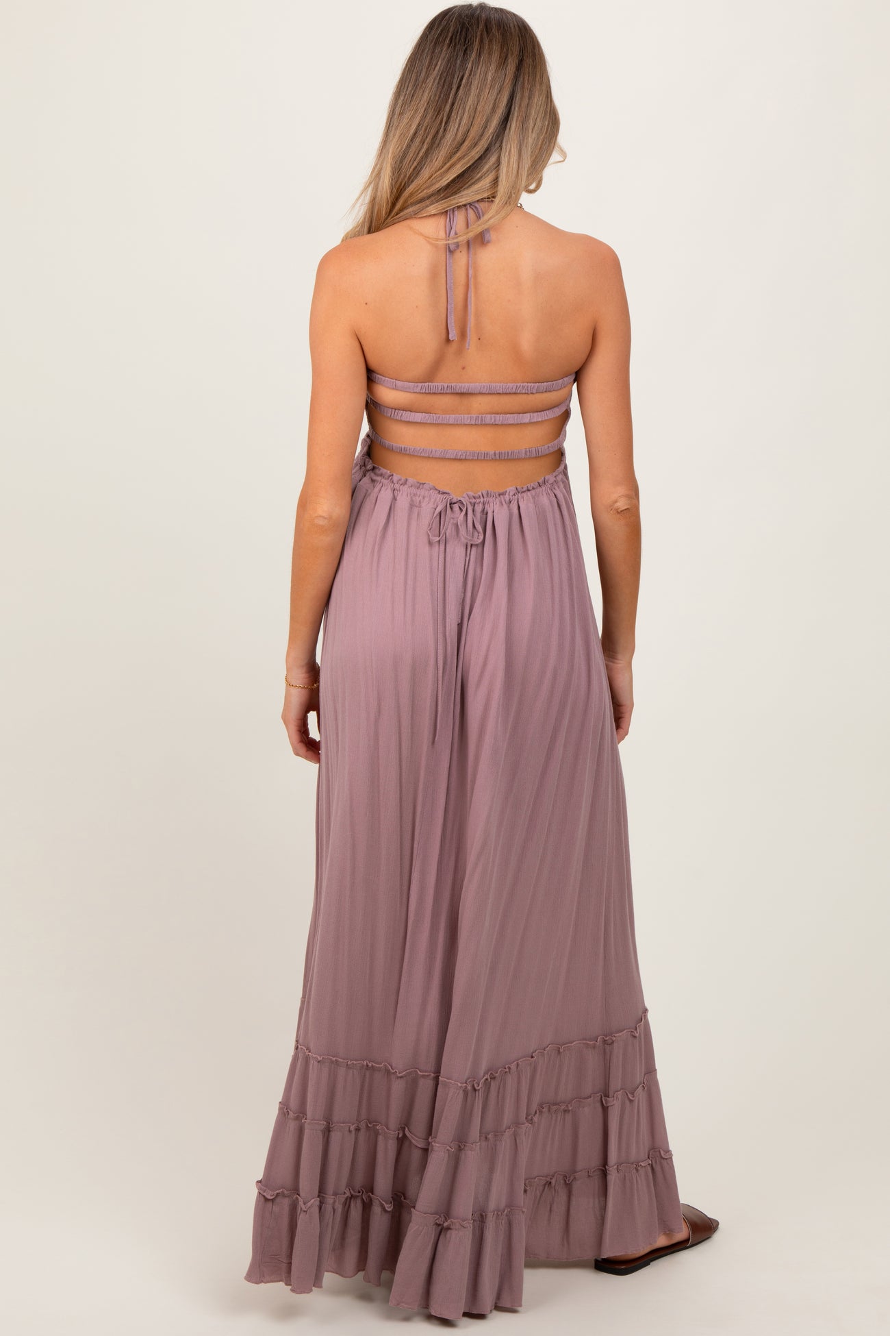 woman wearing a mauve maternity maxi dress with a back tie and ruffle hem, showing her baby bump
