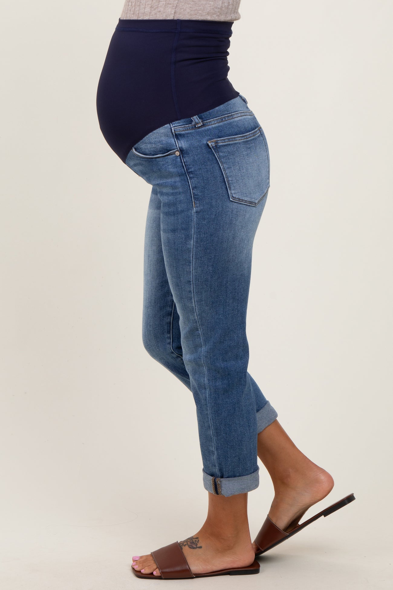 woman wearing blue maternity skinny jeans with a navy belly band and visible baby bump