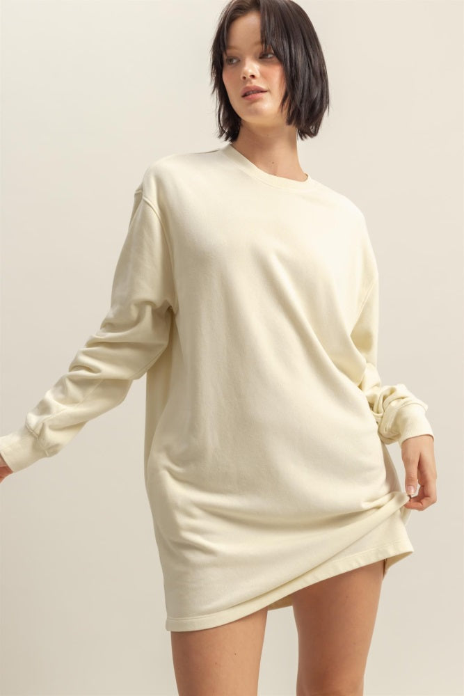 woman wearing a cream oversized sweatshirt dress with long sleeves and a relaxed fit