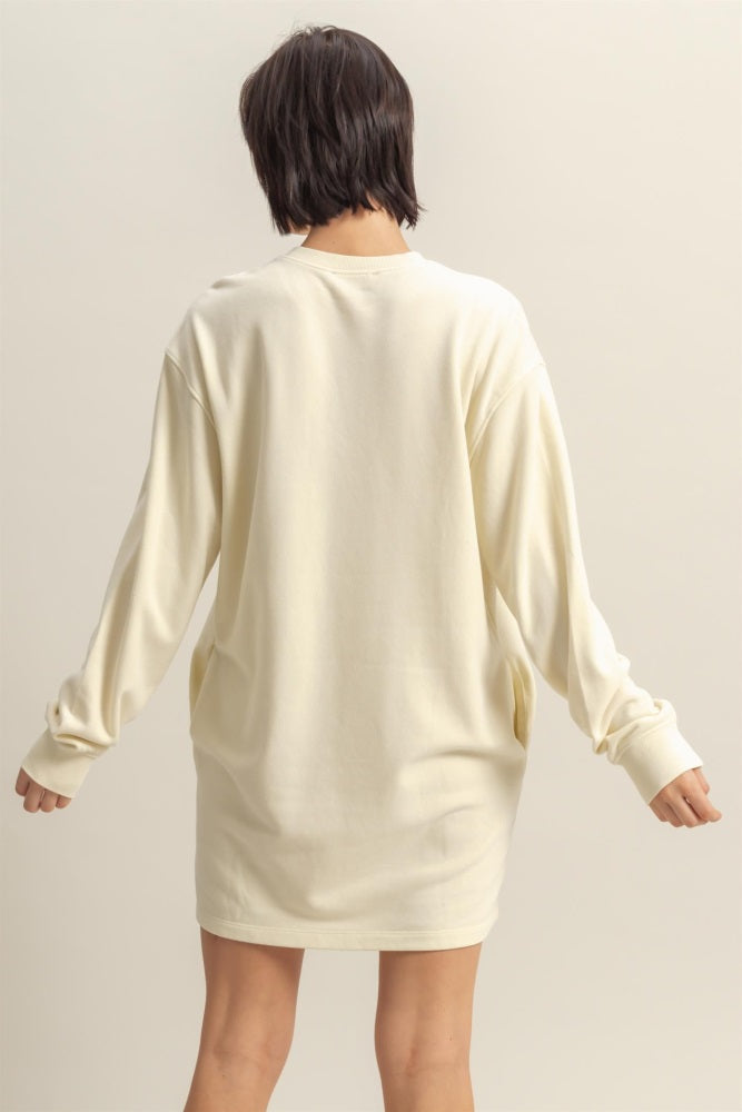 woman wearing a relaxed fit cream long sleeve sweatshirt dress with side pockets