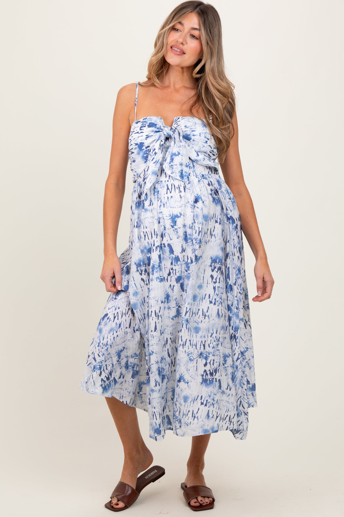 woman wearing a blue and white tie-dye maternity dress with a knot detail at the bust and a flowy skirt, baby bump visible
