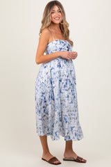 woman wearing a blue and white tie-dye maternity dress with spaghetti straps and a visible baby bump