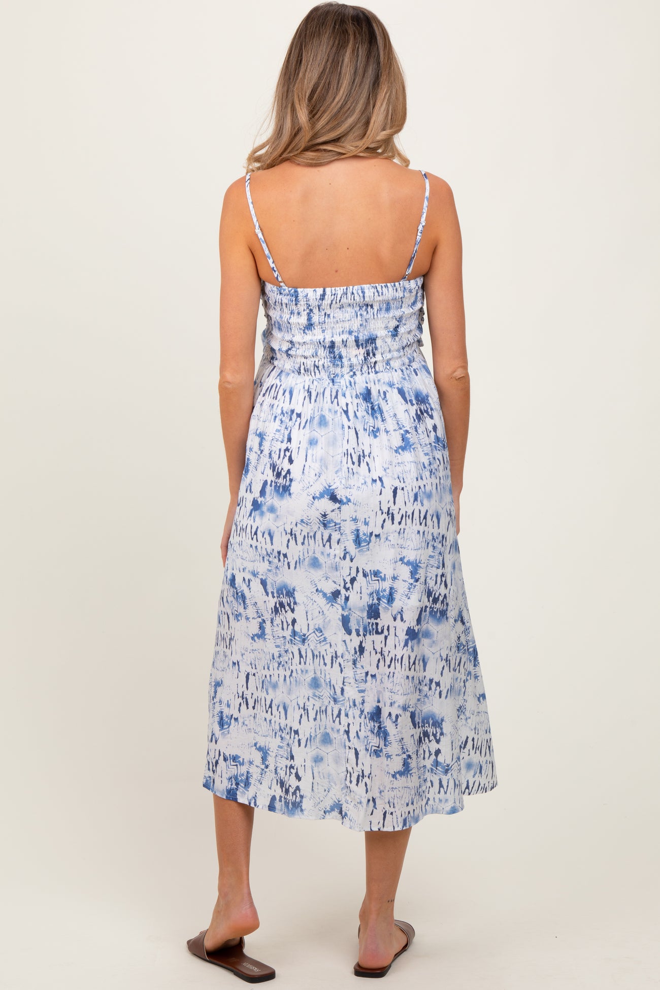 woman wearing a blue and white patterned maternity maxi dress with a smocked back and spaghetti straps.
