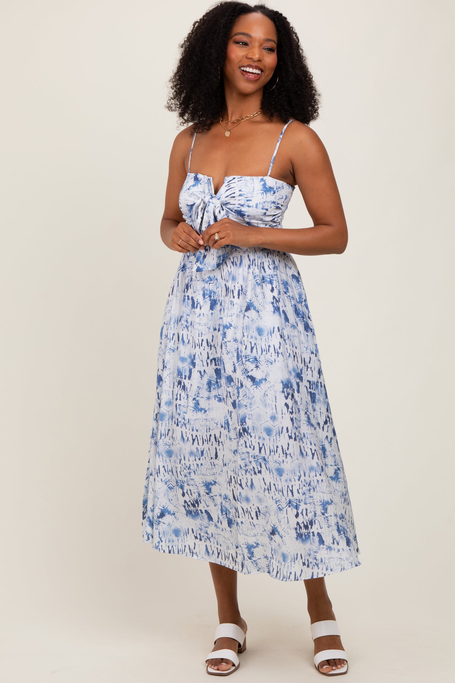 woman wearing a blue and white tie-dye midi dress with a knot detail and spaghetti straps