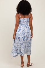 woman wearing a blue and white tie-dye midi dress with spaghetti straps and a smocked back, standing with her back to the camera
