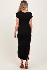 woman wearing a black maternity maxi dress with short sleeves and a side slit, showing her baby bump from behind