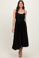woman wearing a black pleated midi dress with spaghetti straps and a tie waist detail