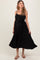 woman wearing a black pleated maternity dress with adjustable straps and a tie waist, showcasing her baby bump