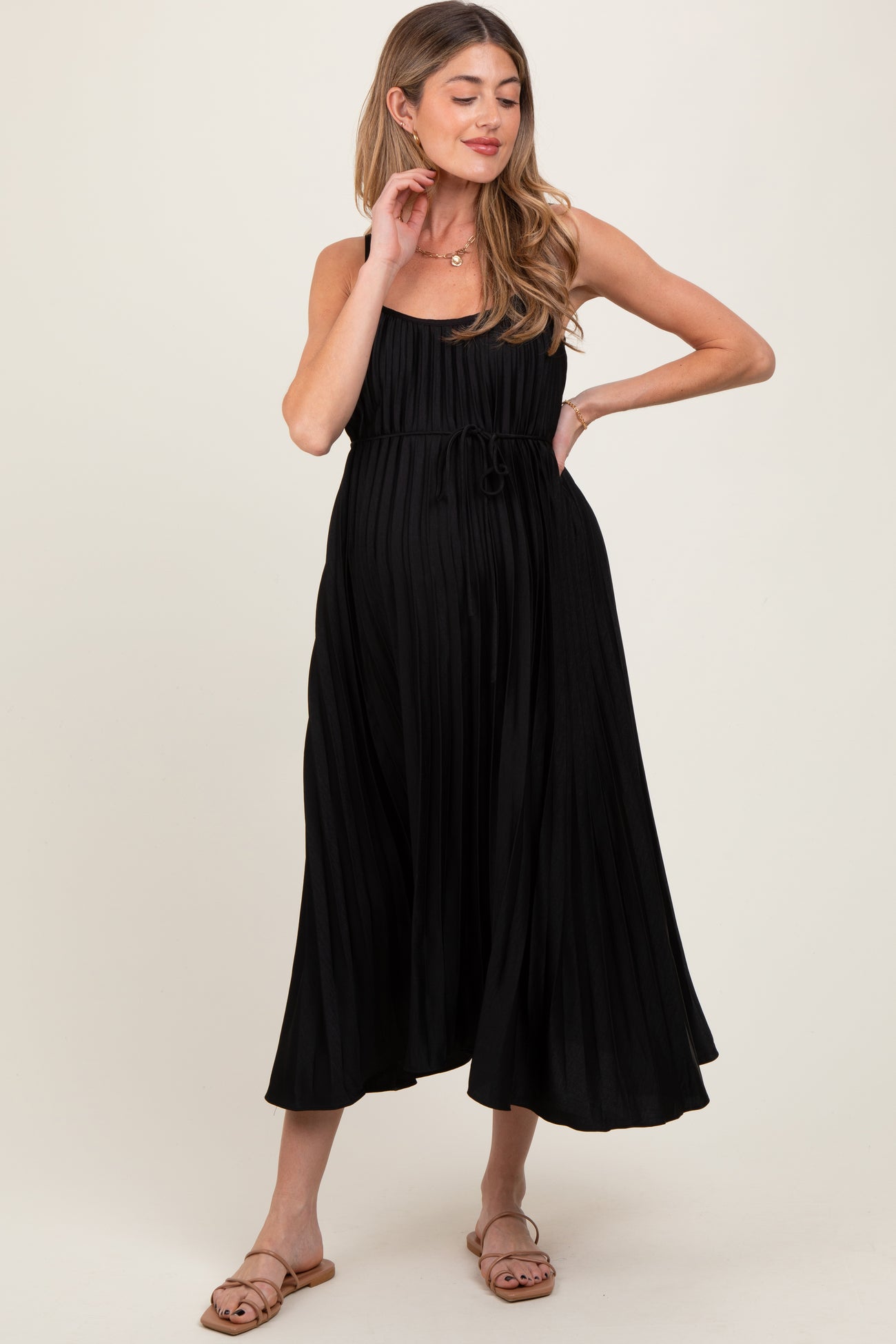 woman wearing a black pleated maternity dress with adjustable tie waist and a baby bump visible