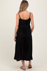 woman wearing a black pleated maternity dress with thin straps, showcasing the back view