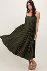 woman wearing a long olive green pleated dress with spaghetti straps and a tied waist detail