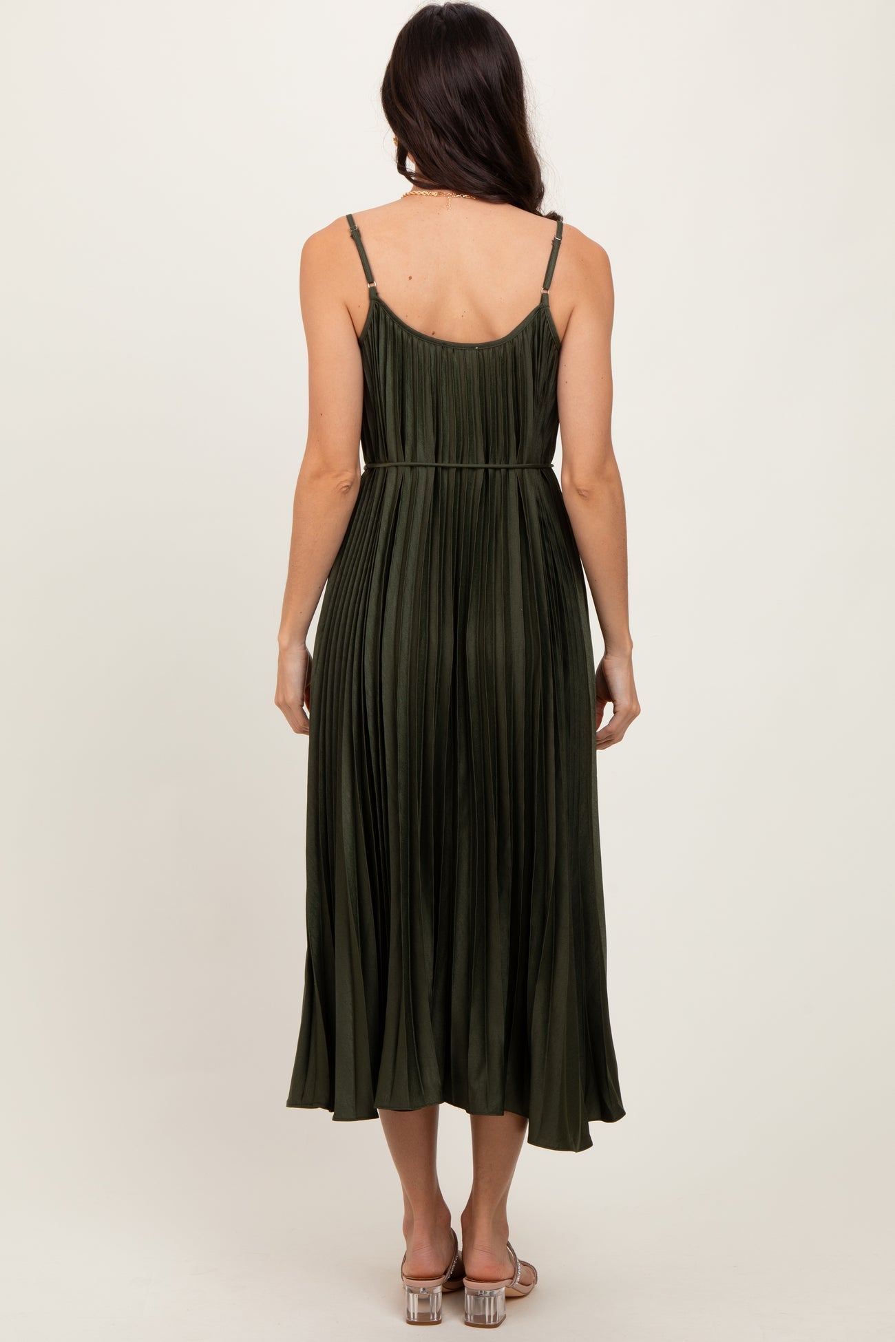 woman wearing an olive green pleated midi dress with adjustable straps, showing the back view
