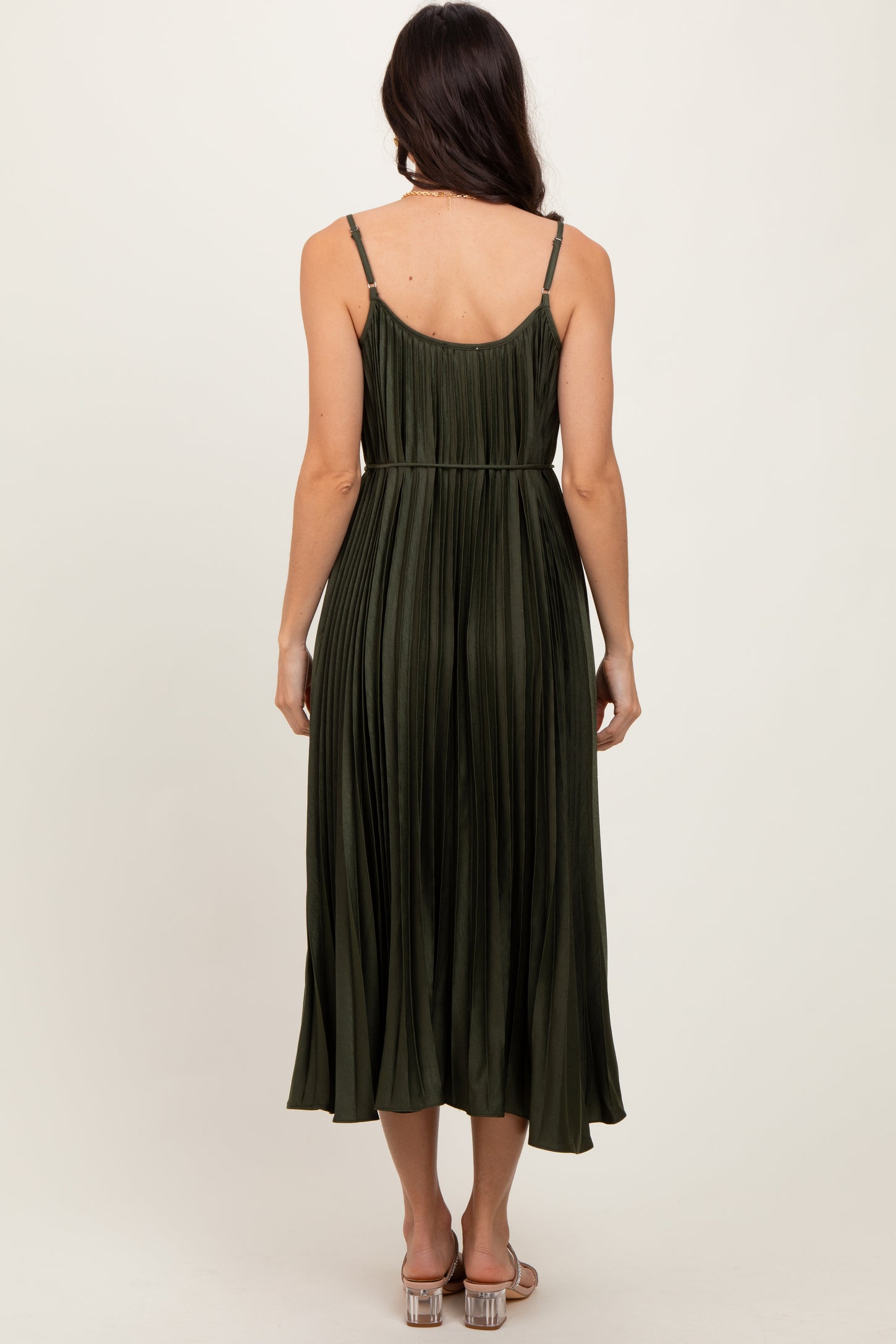 woman wearing an olive green pleated midi dress with adjustable straps, showing the back view