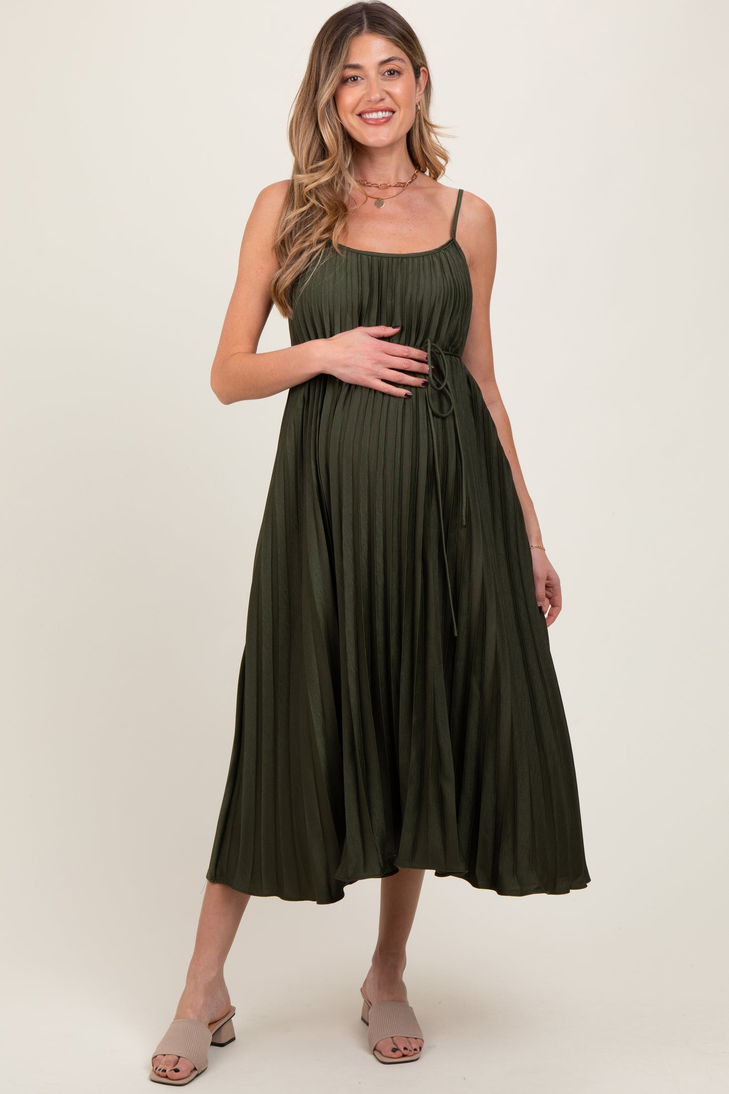 woman wearing a dark green midi maternity dress with a tie waist, holding her baby bump