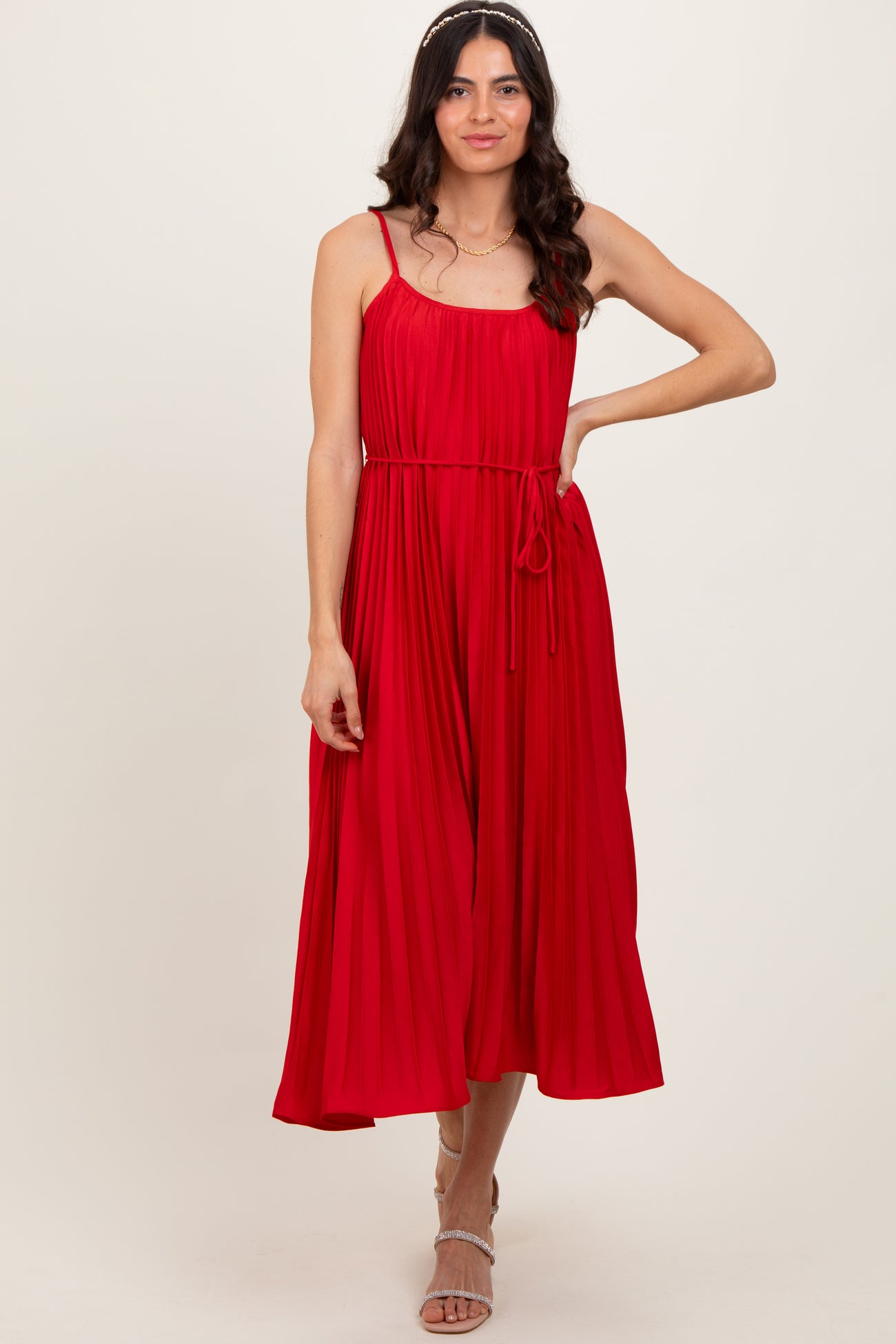 woman wearing a red pleated midi dress with spaghetti straps and a tied waist detail