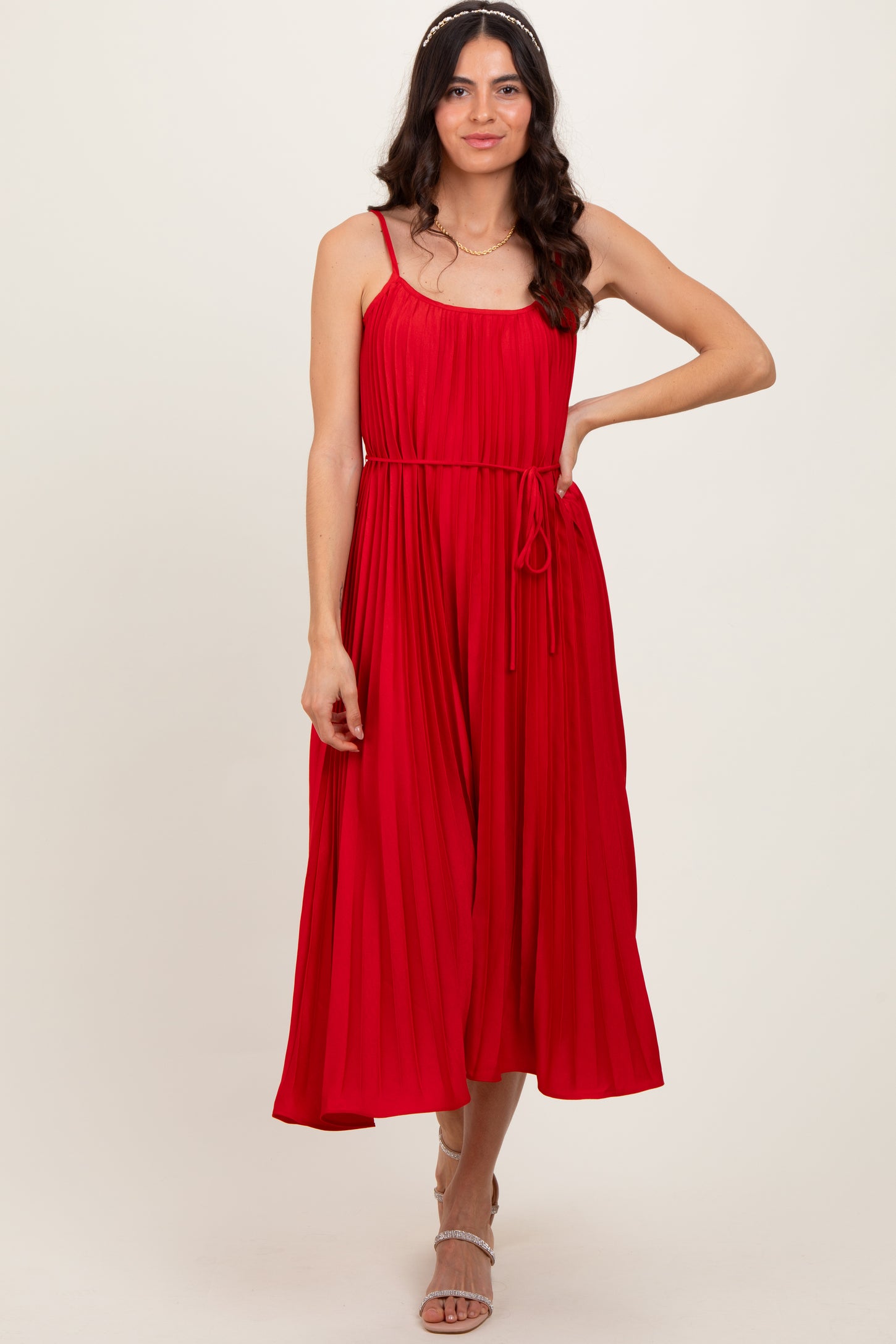 woman wearing a red pleated midi dress with spaghetti straps and a tied waist detail