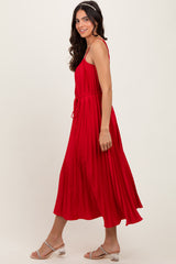 woman wearing a red pleated maxi dress with a tie waist and adjustable straps