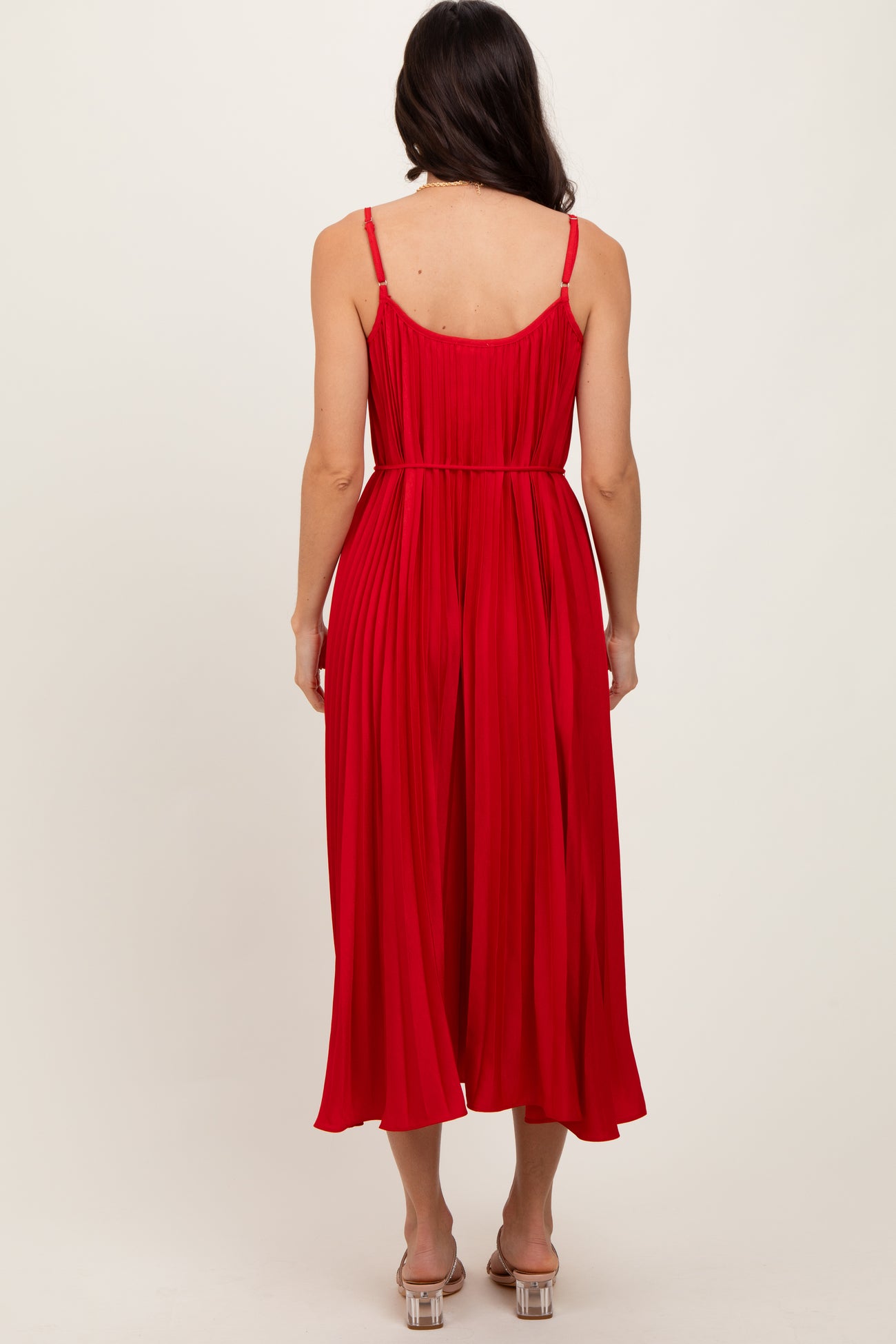 woman wearing a red pleated midi dress with spaghetti straps, viewed from the back
