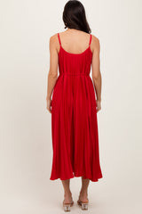 woman wearing a red pleated midi dress with spaghetti straps, viewed from the back