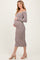 woman wearing a brown and cream striped maternity dress, showing her baby bump, standing sideways
