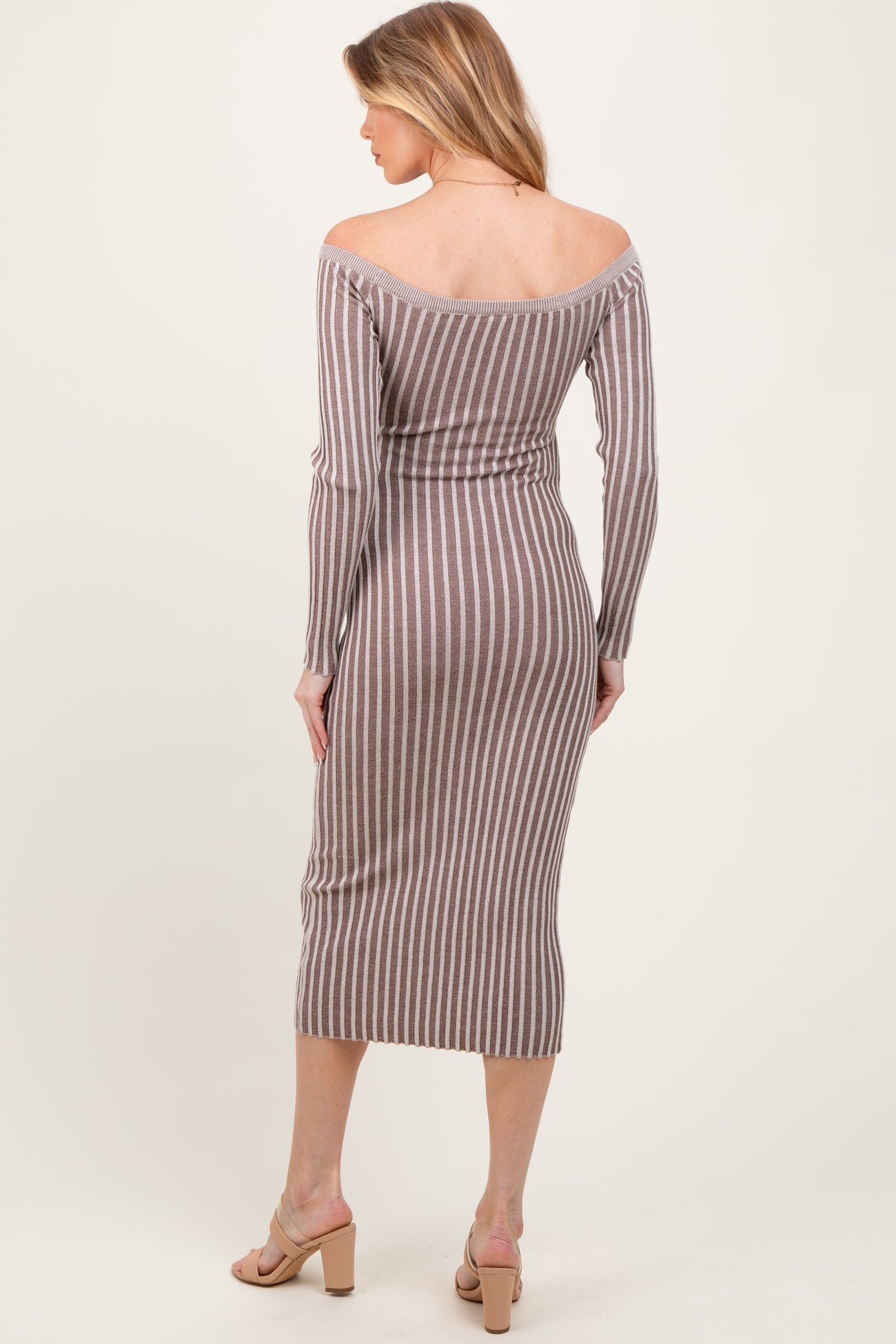 woman wearing a brown and white striped off-shoulder maternity dress, fitted style with long sleeves and mid-calf length