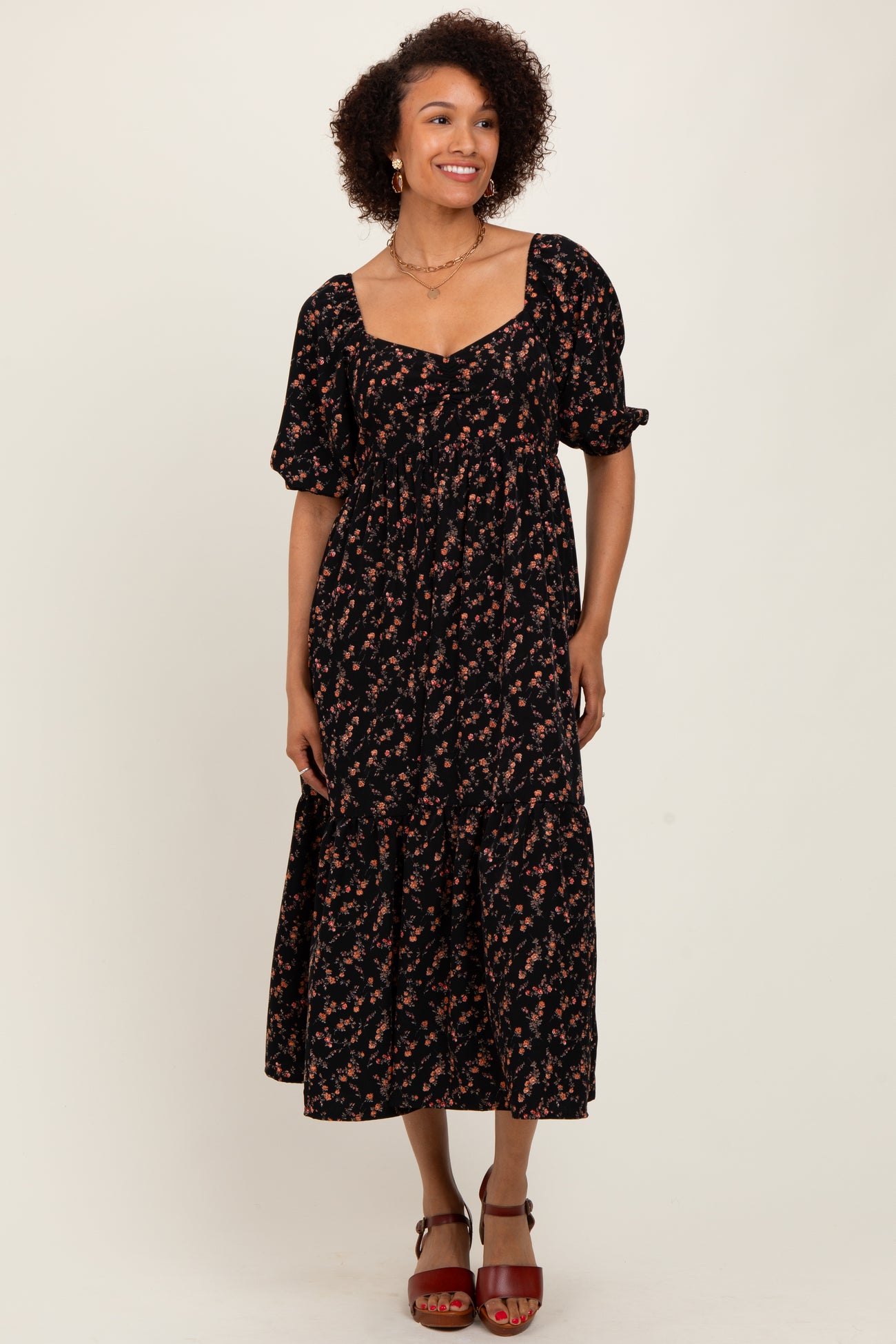 woman wearing a black floral midi dress with puff sleeves and a square neckline