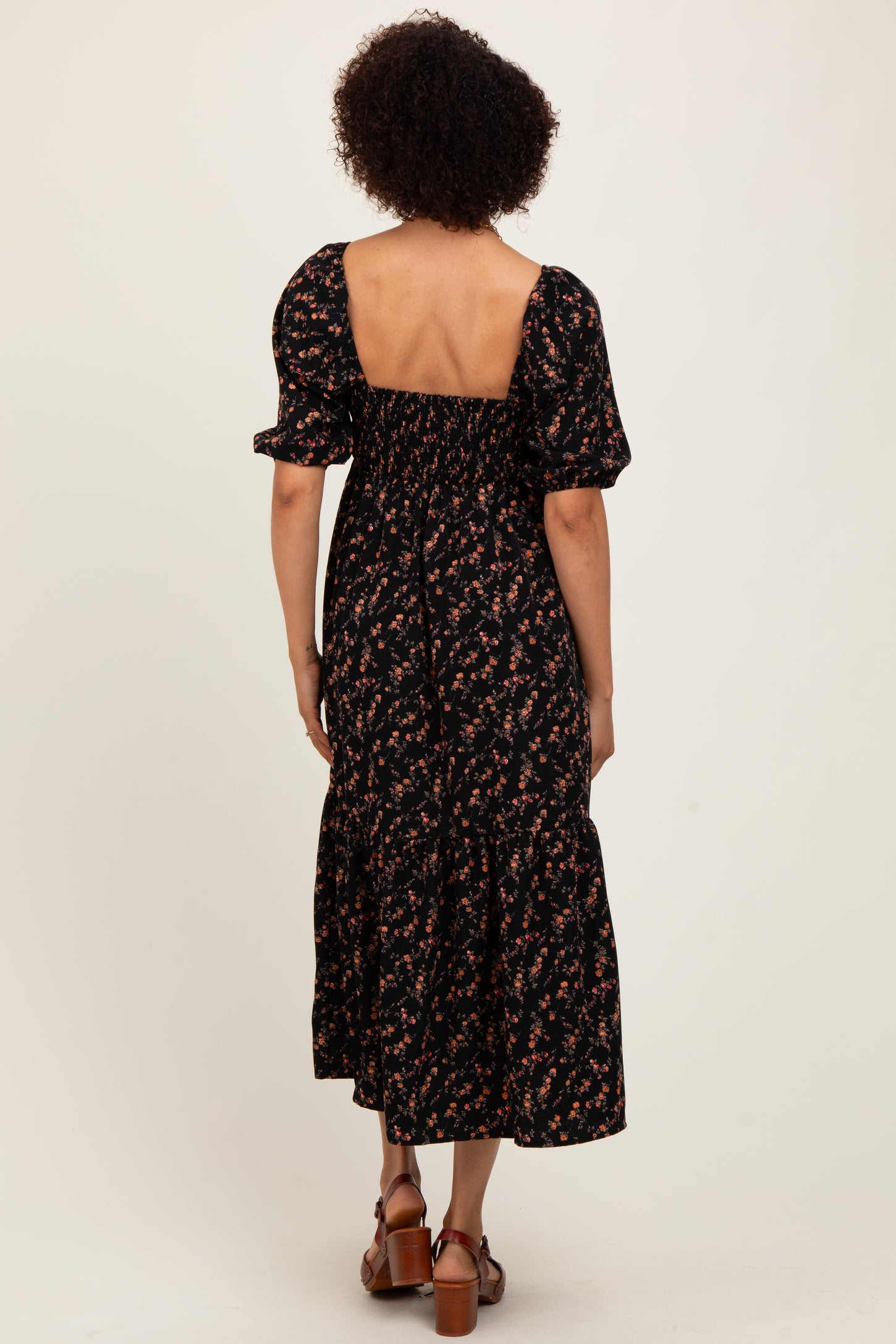 woman wearing a black floral maxi dress with puff sleeves and a smocked back