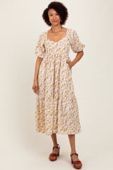 woman wearing a white floral midi dress with puff sleeves and pockets, standing against a plain background