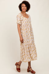 woman wearing a white floral midi dress with puffed sleeves and a square neckline, standing against a plain background
