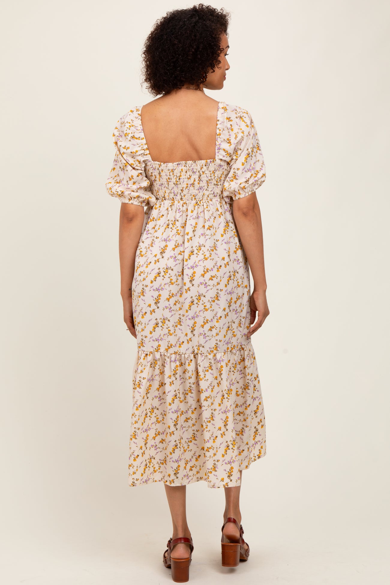 woman wearing a white floral midi dress with puff sleeves and a smocked back, showing the back view