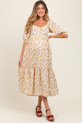 woman wearing a white floral maternity dress with puffed sleeves and a tiered hem, showing her baby bump