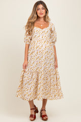 woman wearing a floral maternity dress with puffed sleeves and a tiered skirt, showcasing her baby bump