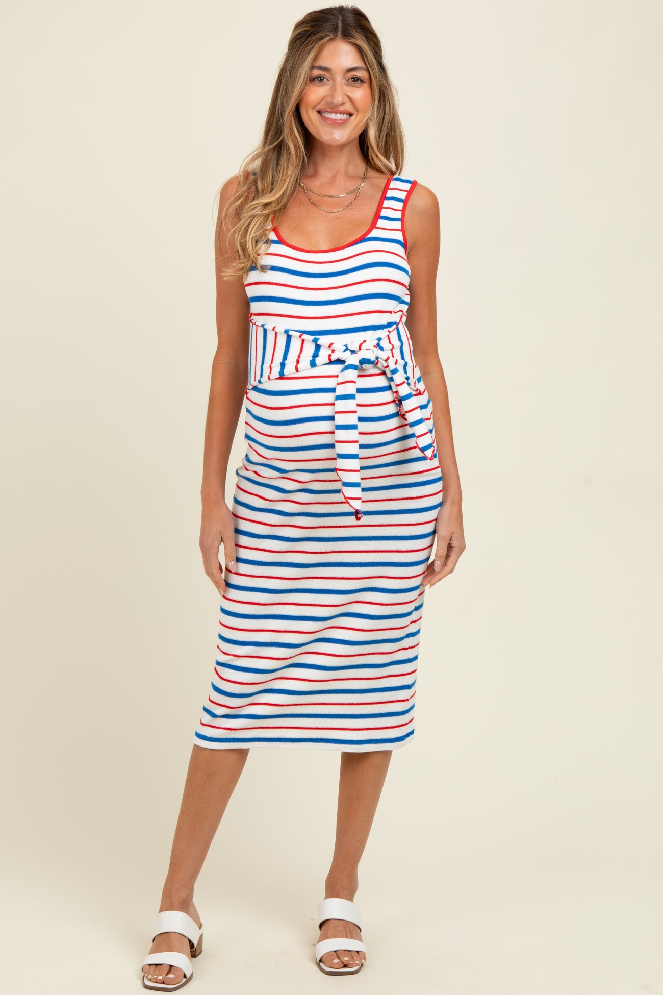 woman wearing a striped maternity dress with a tie waist, featuring red, blue, and white stripes and a visible baby bump