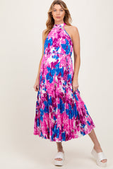 woman wearing a colorful floral print maternity dress with a halter neckline and flowing pleated skirt, baby bump visible