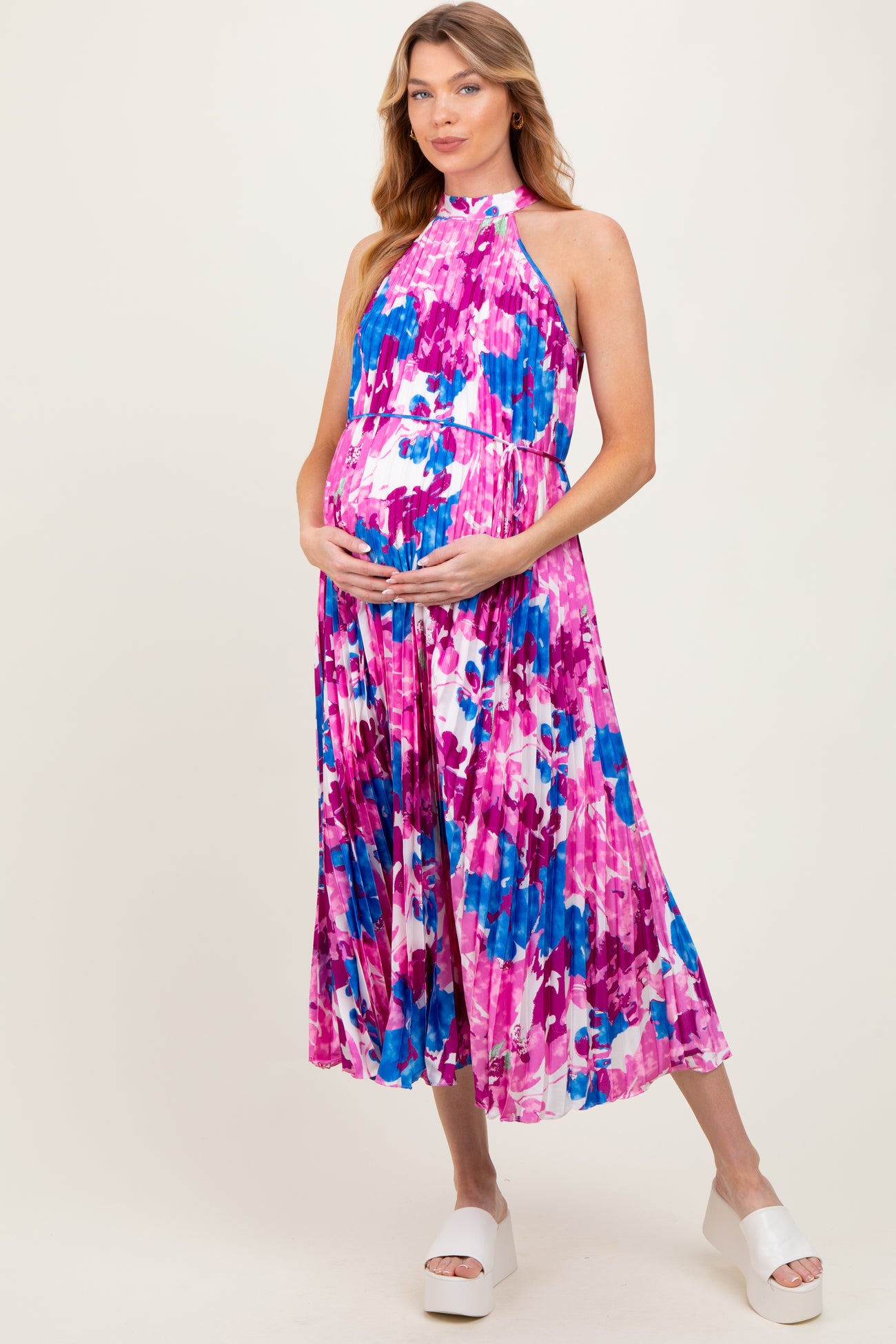 woman wearing a colorful floral maternity maxi dress and holding her baby bump