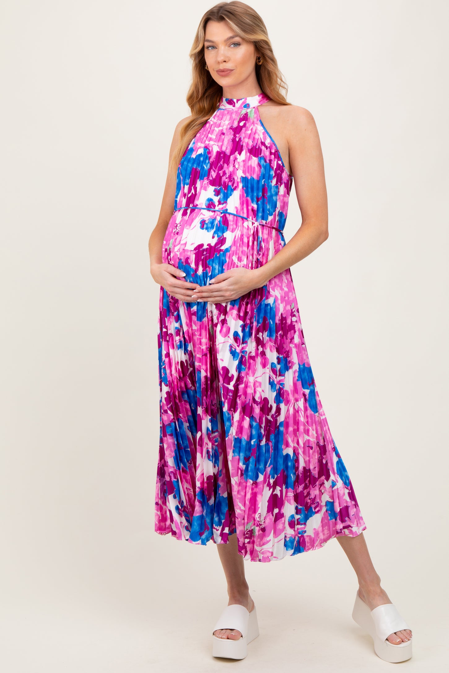 woman wearing a colorful floral maternity maxi dress and holding her baby bump