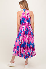 woman wearing a colorful floral maternity dress with a halter neck and pleated skirt, showcasing a baby bump