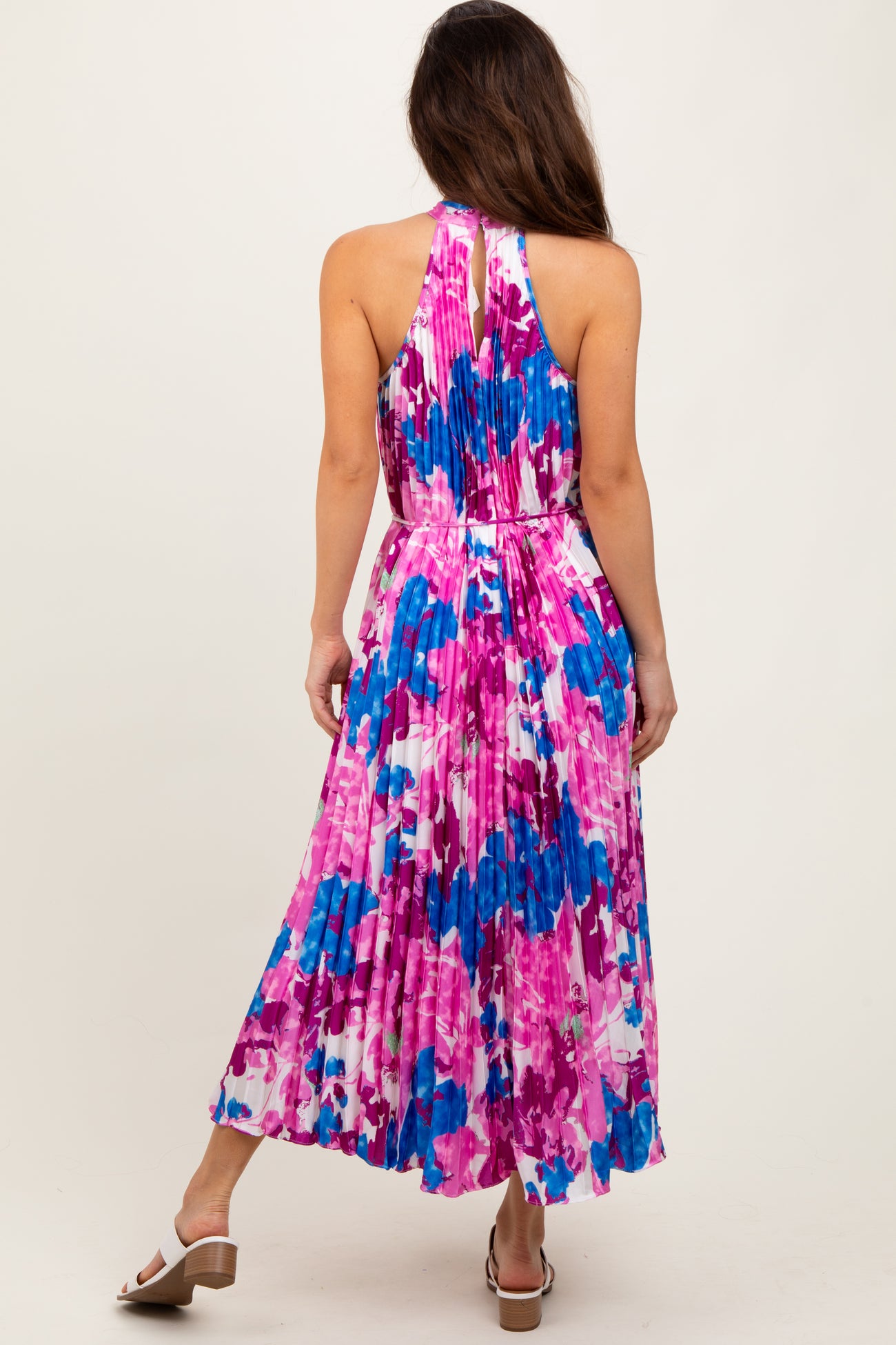 woman wearing a colorful halter neck pleated maxi dress with a floral print in pink and blue