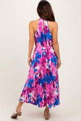 woman wearing a colorful halter neck pleated maxi dress with a floral print in pink and blue