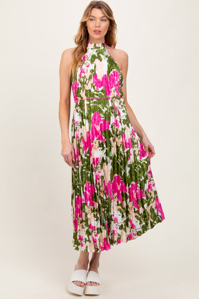woman wearing a floral maternity dress with pink and green patterns, styled with a halter neck and pleated skirt