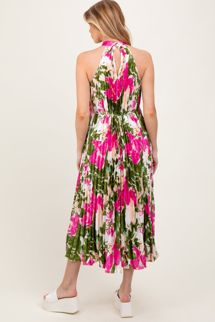 woman wearing a floral maternity dress with a halter neck and pleated skirt, featuring pink and green colors