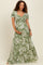 woman wearing a green floral maternity maxi dress and cradling her baby bump