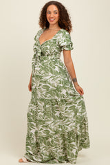 woman wearing a green floral print maternity maxi dress with short puff sleeves and a smocked bodice, showing her baby bump