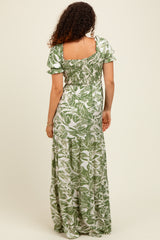 woman wearing a green floral maternity maxi dress with smocked bodice and short puff sleeves, back view