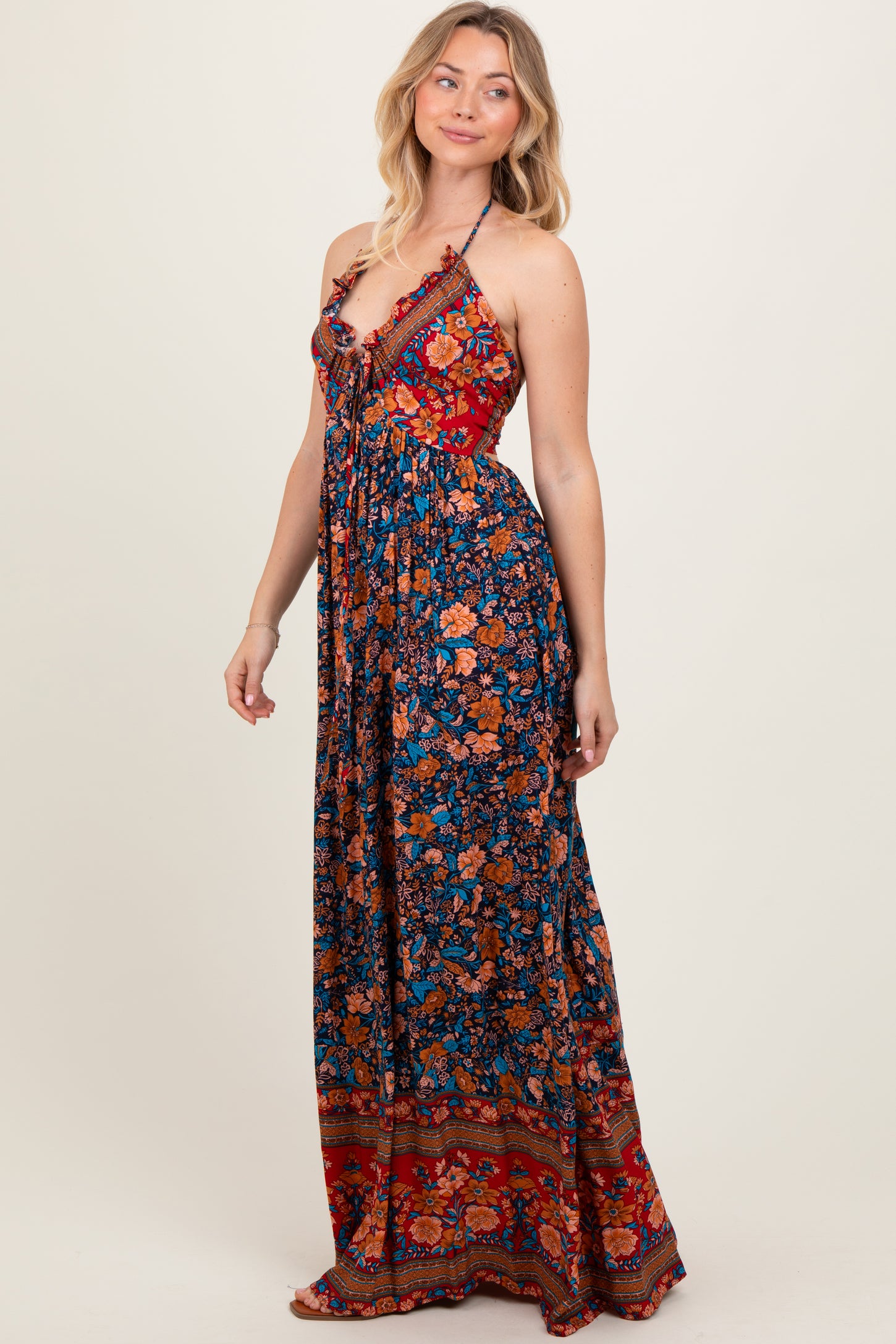 woman wearing a floral maxi dress with a halter neck and tiered design in blue and red tones